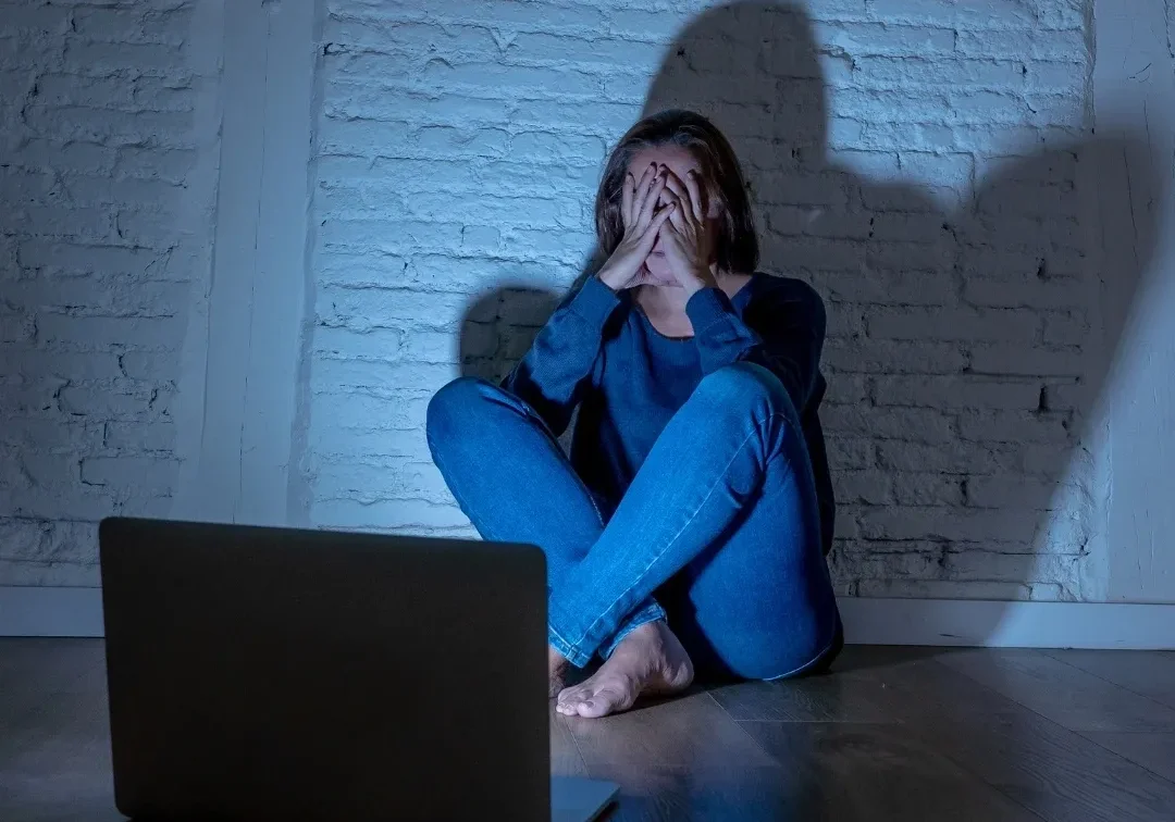 A woman sitting on the floor in front of a laptop.